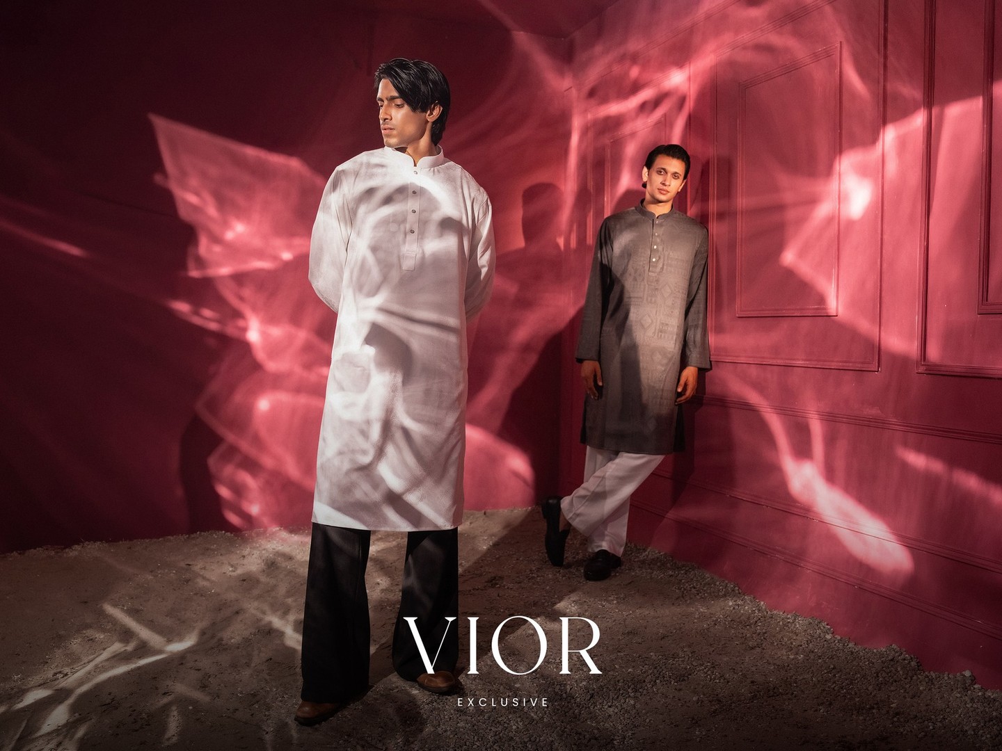 Two men in VIOR panjabis in the red room, light playing across the walls around the VIOR Exclusive wordmark