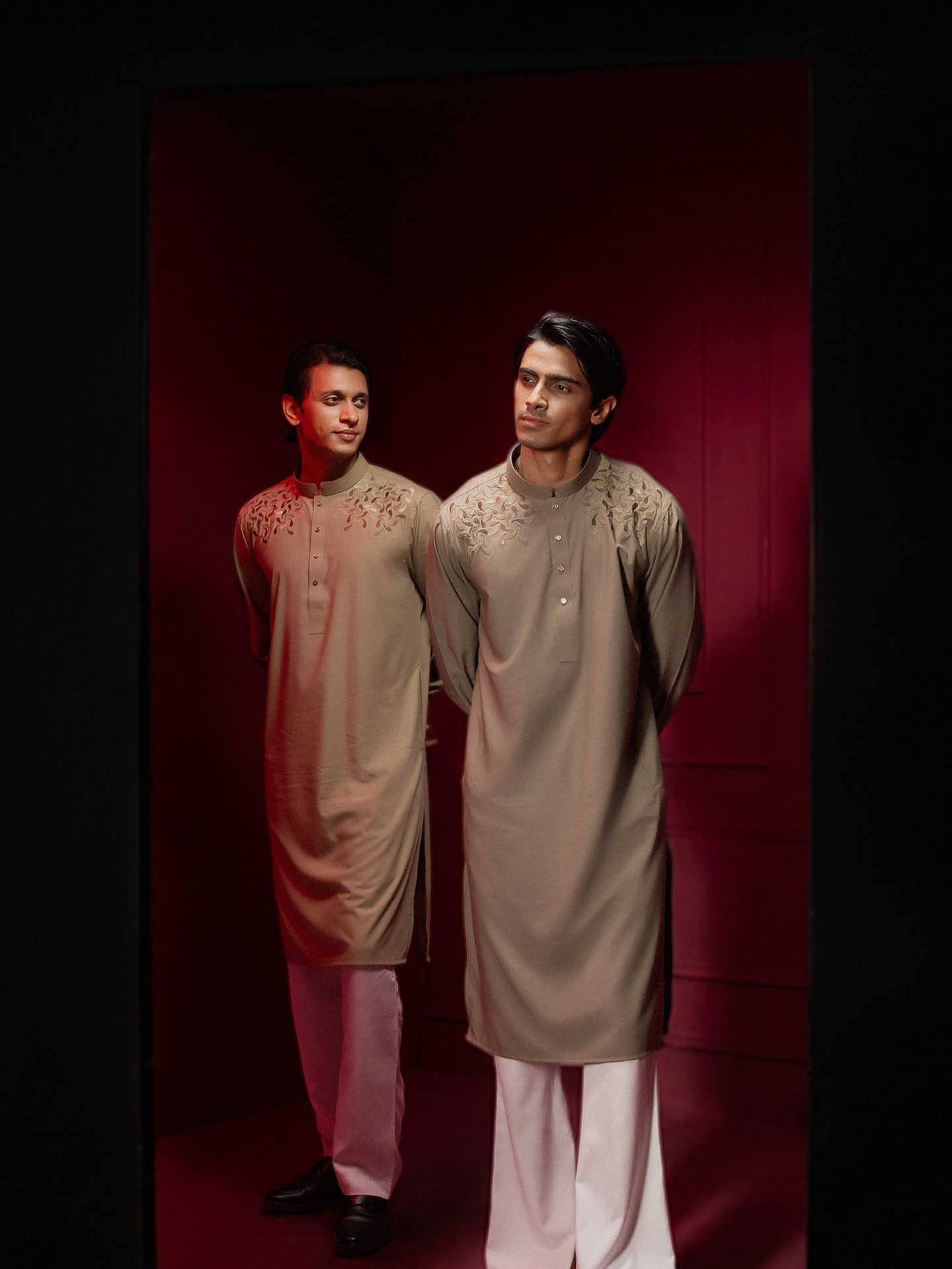 Two men in VIOR panjabis in the red room, light playing across the walls