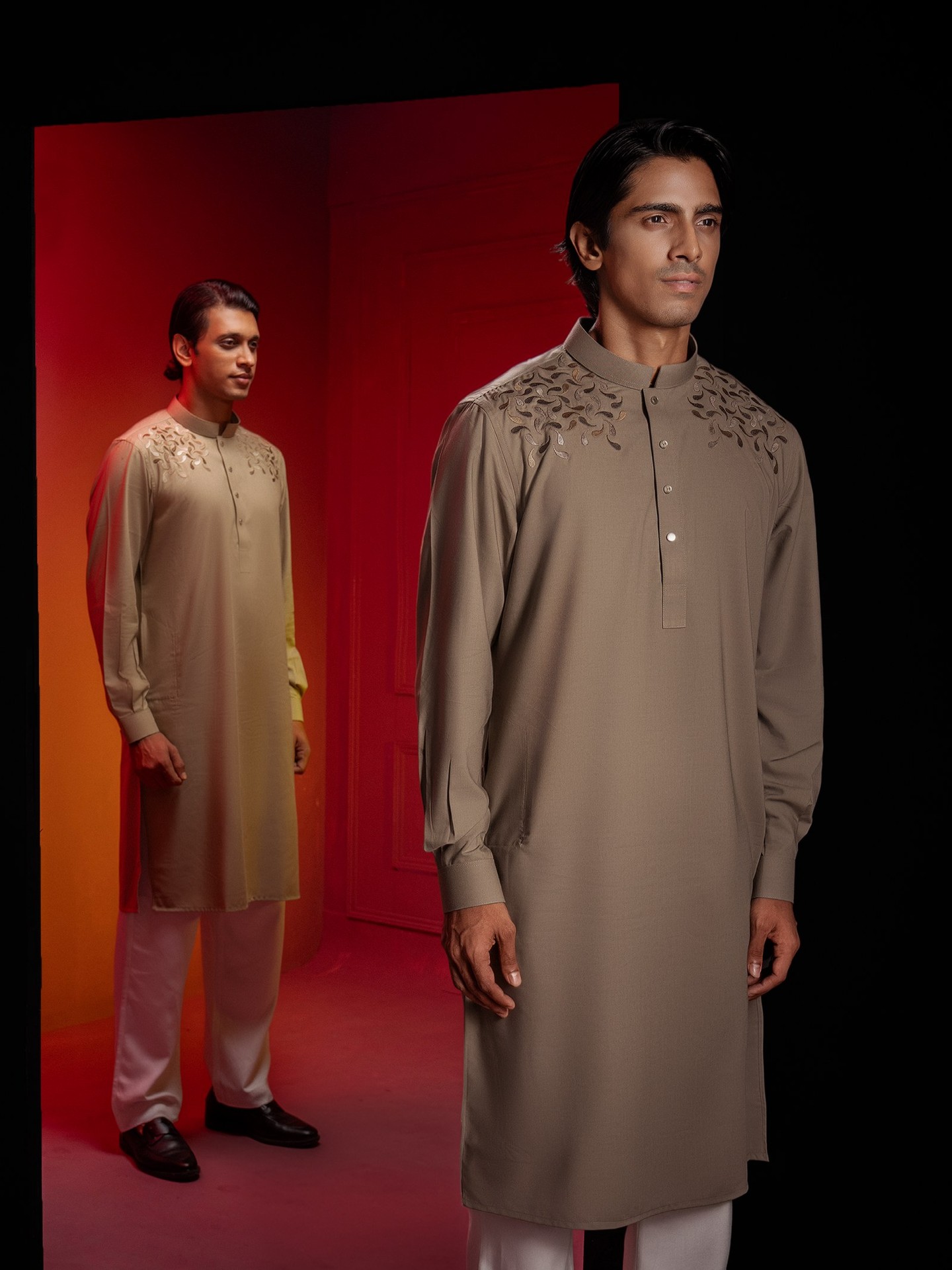 Men in embroidered VIOR panjabis in the black door frame of the red room